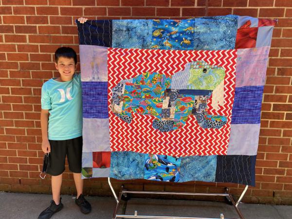 Boy with completed quilt top at Creativity Shell