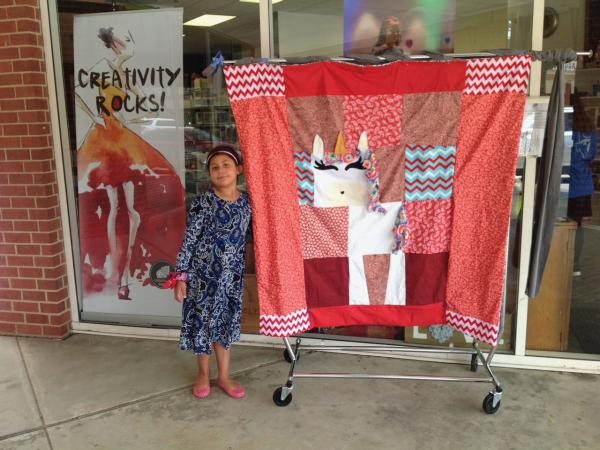 Young sewist with her unicorn quilt at Creativity Shell